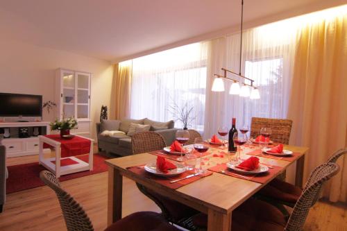 un salon avec une table en bois et des verres à vin dans l'établissement Haus Heidi, à Westerland