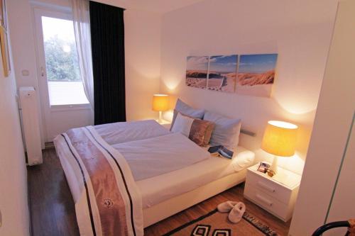 une chambre avec un lit et deux lampes et une fenêtre dans l'établissement Haus Heidi, à Westerland