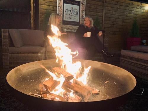 two women sitting in front of a fire pit at Lairds Lodge Inverness in Inverness