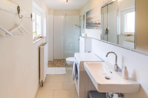 ein weißes Bad mit einem Waschbecken und einem WC in der Unterkunft Haus Seeblick II in Glücksburg