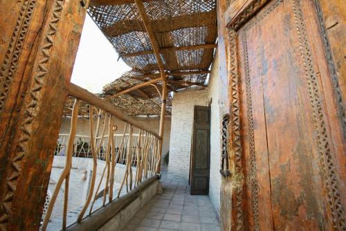 um corredor num edifício antigo com tecto de madeira em Amulet Hotel em Bukhara