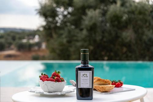 eine Flasche Wein auf einem Tisch mit einer Schale Erdbeeren in der Unterkunft Relais Trulli Le Icone in Ostuni