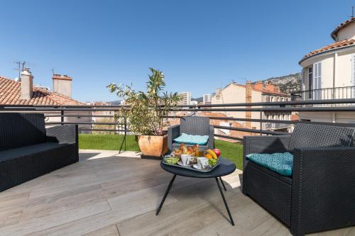 a patio with two chairs and a table with a tray of food at Celenya Hôtel in Toulon