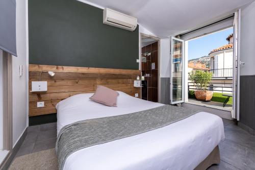 a bedroom with a large bed and a large window at Celenya Hôtel in Toulon