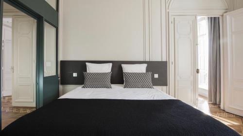 a bedroom with a large bed with black and white pillows at MiHotel Gailleton in Lyon