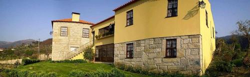 duży żółty budynek na wzgórzu z zieloną trawą w obiekcie Quinta do Pomarinho w mieście Arouca