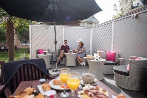 a man and woman sitting on a patio under an umbrella at Hôtel La Villefromoy in Saint Malo