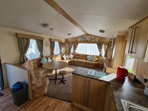 a living room with a couch and a table in a caravan at Golden Palm - Meadow Lakes in Chapel Saint Leonards