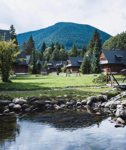 a stream of water with houses in the background at Hotel****Liptovský dvor in Liptovský Ján