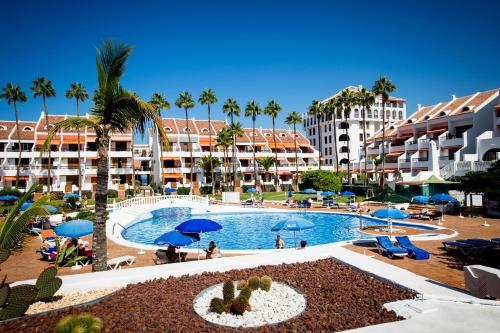 un complejo con piscina, palmeras y edificios en GO2TENERIFE Tropicana Villa Santiago 2, en Playa de las Américas