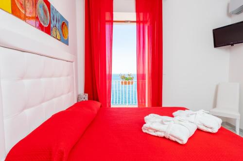 een slaapkamer met een rood bed en handdoeken erop bij Donna Giulia in Amalfi