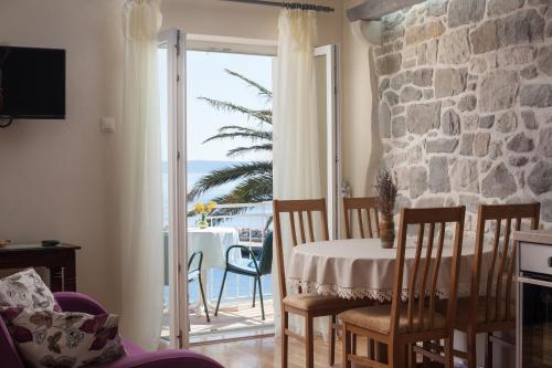 ein Wohnzimmer mit einem Tisch und einem Balkon mit Meerblick in der Unterkunft Apartman Vite in Podgora
