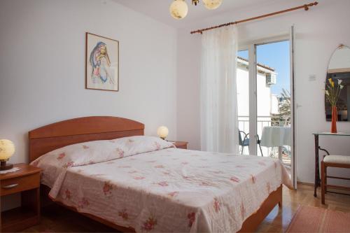ein Schlafzimmer mit einem großen Bett und einem Balkon in der Unterkunft Apartman Vite in Podgora