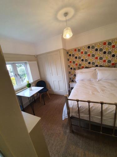 a bedroom with a bed and a table and a window at The Lodge Stanwell in Stanwell