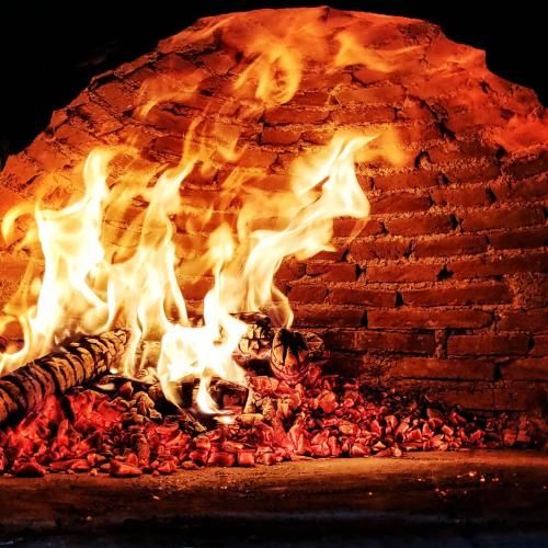 a fire burns in a brick oven at Matilde's Chalet Etna Nature House in Nicolosi