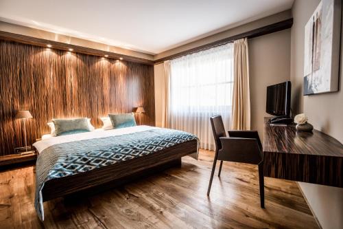 a bedroom with a bed and a desk and a television at Hotel Restaurant Spa Torkel in Nonnenhorn