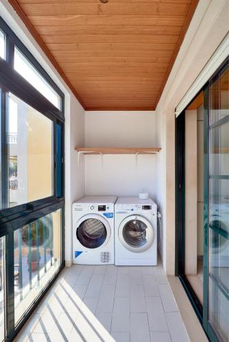 a laundry room with a washer and dryer next to a window at Carcavelos Apartment in Carcavelos