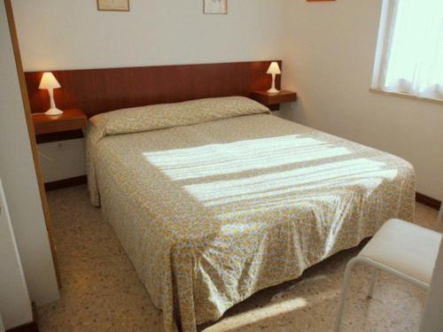 a bedroom with a bed and two lamps on two tables at Lignano cheap in Lignano Sabbiadoro