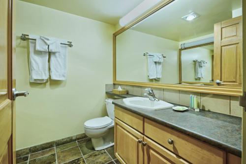 uma casa de banho com um lavatório, um WC e um espelho. em Mountainside Lodge em Whistler