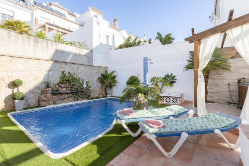 a backyard with a swimming pool and two lounge chairs at Villa Maite in Nerja