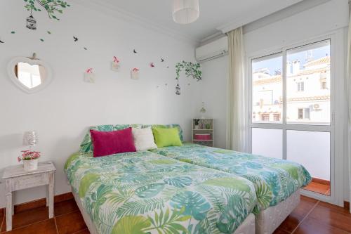 a bedroom with a bed with colorful pillows and a window at Villa Maite in Nerja