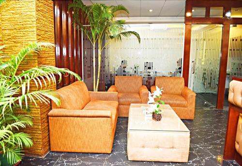 a lobby with couches and a coffee table and plants at West Park Inn in Dhaka