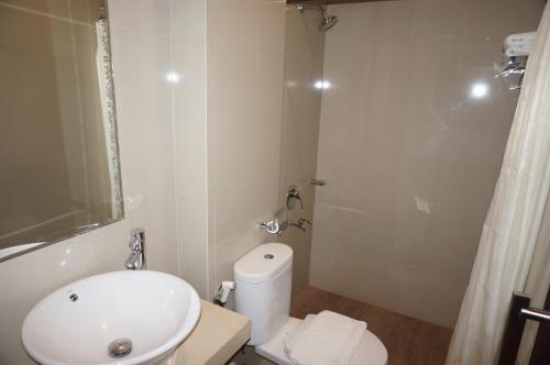 a white bathroom with a toilet and a shower at Nueve Malioboro Hotel Yogyakarta in Yogyakarta