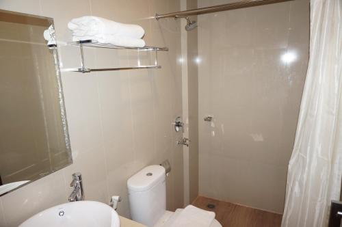 a bathroom with a white toilet and a shower at Nueve Malioboro Hotel Yogyakarta in Yogyakarta