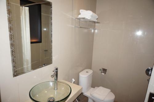 a bathroom with a sink and a toilet and a mirror at Nueve Malioboro Hotel Yogyakarta in Yogyakarta