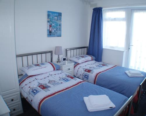 een slaapkamer met 2 bedden en een raam bij Sunny View, 87 Brambles Chine in Freshwater