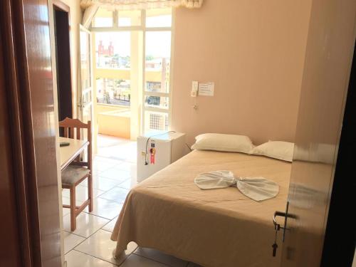Vyalle Hotel في ماشادينهو: غرفة نوم مع سرير مع ربط القوس عليه