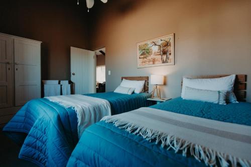 two beds in a room with blue sheets at Sionshoop in Van Wyksdorp