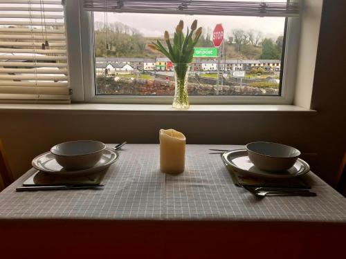 a table with two plates and a candle and a window at Corner House in Newport