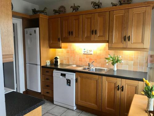 a kitchen with wooden cabinets and a white refrigerator at Corner House in Newport