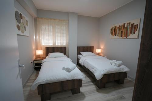two beds in a room with white sheets at Apartman Nastasijevic in Kladovo