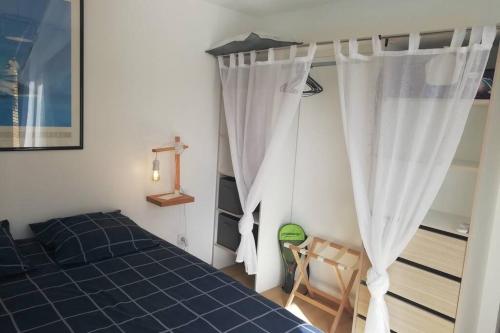1 dormitorio con cama azul y cortinas blancas en Entre Piscine et Mer, en Tonnay-Charente