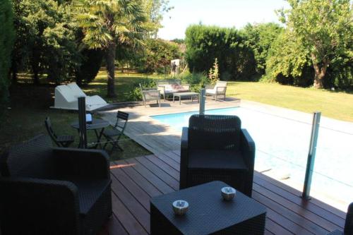 une terrasse avec des chaises et des tables ainsi qu'une piscine dans l'établissement Entre Piscine et Mer, à Tonnay-Charente