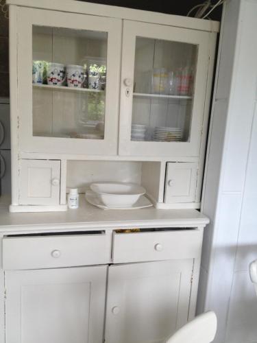 un armario blanco con puertas de cristal en la cocina en Petite house en Starigrad-Paklenica