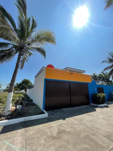 a garage with a palm tree in front of a house at Chalet en Puerto San Jose in San José de Guatemala