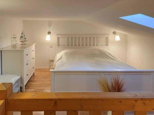 a bedroom with a large white bed and a dresser at Ferienwohnung Lagune Göhren in Göhren