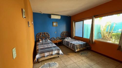 two beds in a room with blue walls and a window at Chalet en Puerto San Jose in San José de Guatemala