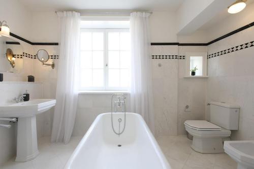 a bathroom with a tub and a toilet and a sink at Ferienwohnung Art Deco in Hörnum