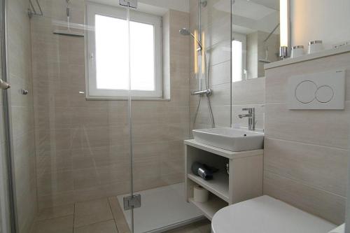 a bathroom with a shower and a toilet and a sink at Budersand 26 in Hörnum