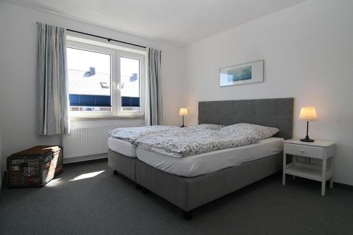 een slaapkamer met een groot bed en een raam bij Berliner Ring 5/23 in Hörnum
