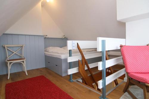 ヘルヌムにあるFerienwohnung Dünennestのベッドルーム1室(二段ベッド1台、椅子、赤いラグ付)