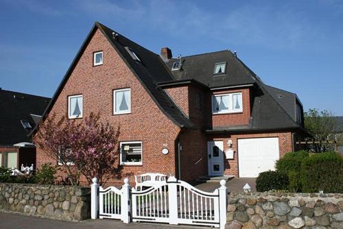 a large brick house with a white fence at Haus Gräpel App 1 in Hörnum