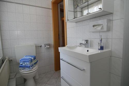 a white bathroom with a toilet and a sink at Haus Gräpel App 2 in Hörnum