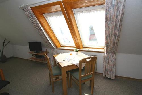 ヘルヌムにあるHaus Gräpel App 5のテーブルと椅子、窓が備わる客室です。
