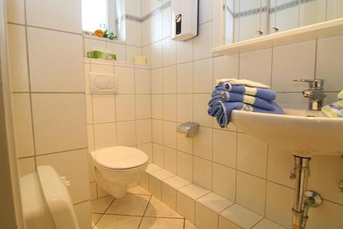 a white bathroom with a toilet and a sink at Haus Gräpel App 6 in Hörnum