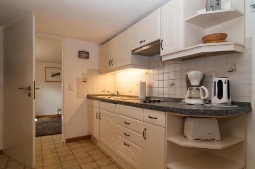 eine Küche mit weißen Schränken und einer Arbeitsplatte in der Unterkunft Haus Möwe 5/22 in Hörnum